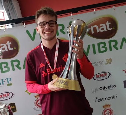 Homem de camiseta vermelha segurando um troféu